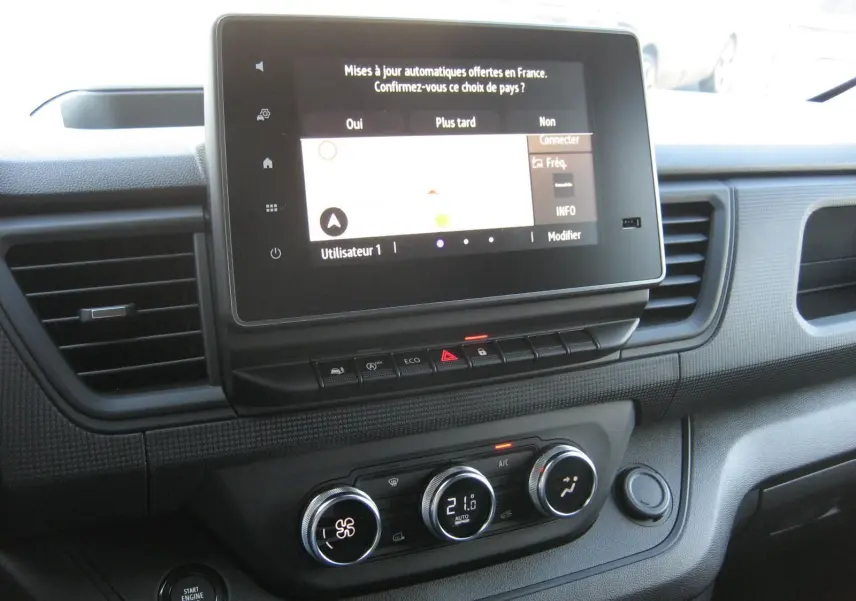 Tableau de bord du Renault Trafic Fourgon gris Comète 2025 avec écran tactile et commandes climatisation visibles.