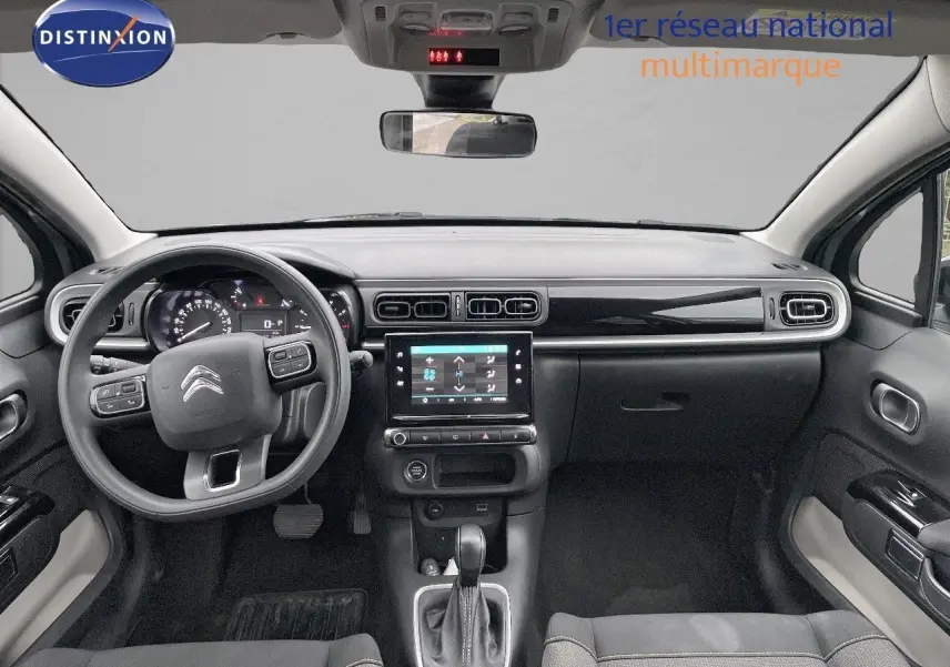 Vue intérieure frontale du tableau de bord et volant du Citroën C3 2023 gris acier avec toit noir et écran tactile central.