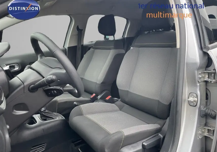 Vue intérieure côté conducteur de la Citroën C3 2023 gris acier, montrant sièges tissu gris et volant noir.