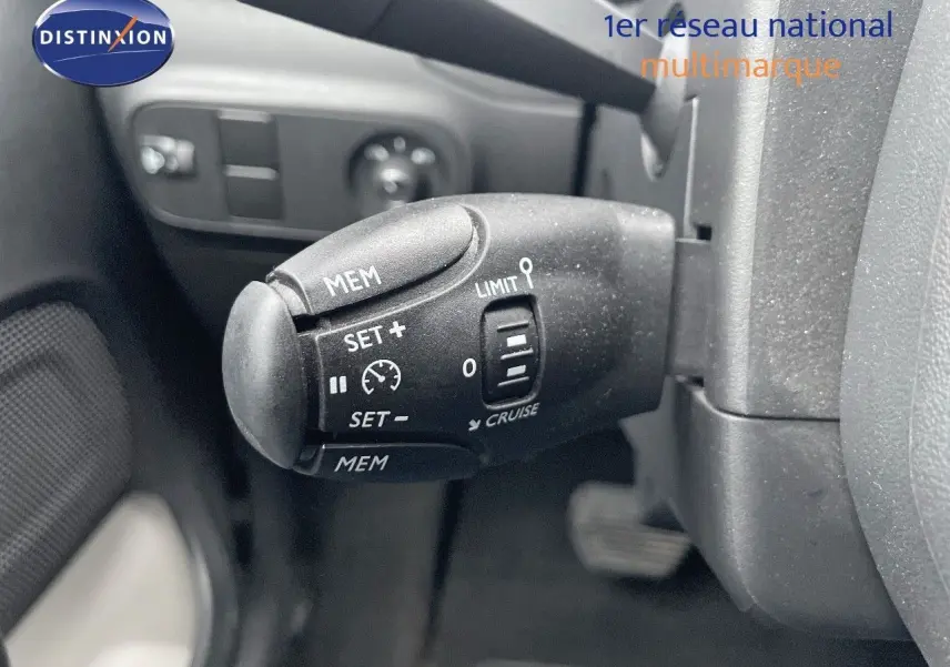 Gros plan sur la commande de régulateur de vitesse d'une Citroën C3 2023 gris acier avec toit noir, côté gauche du volant.