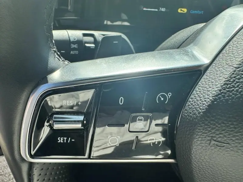 Gros plan sur les commandes au volant cuir noir du Renault Espace gris Schiste 2024, avec régulateur de vitesse et aides à la conduite.