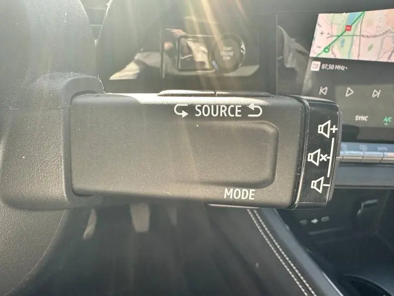 Gros plan sur la commande audio au volant du Renault Espace gris schiste 2024, avec touches source et mode visibles.