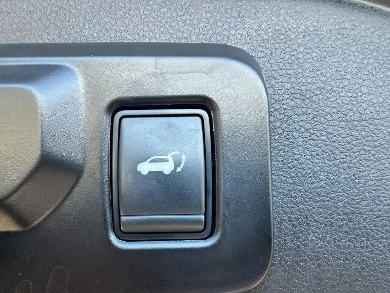 Bouton noir de commande d'ouverture du coffre sur tableau de bord du Renault Espace gris Schiste 2024.