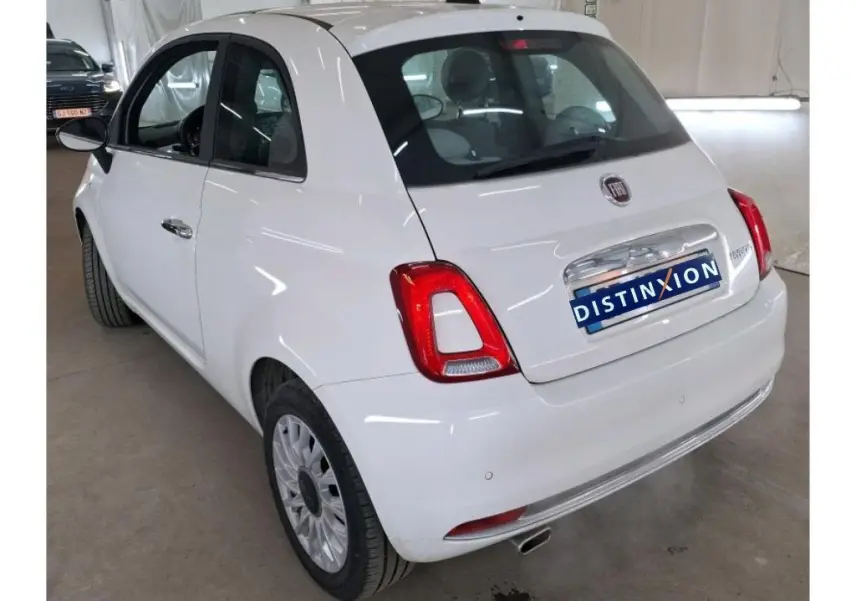 Vue 3/4 arrière droite d'une FIAT 500 blanche DolceVita Plus 2022 avec feux arrière rouges et jantes spécifiques.