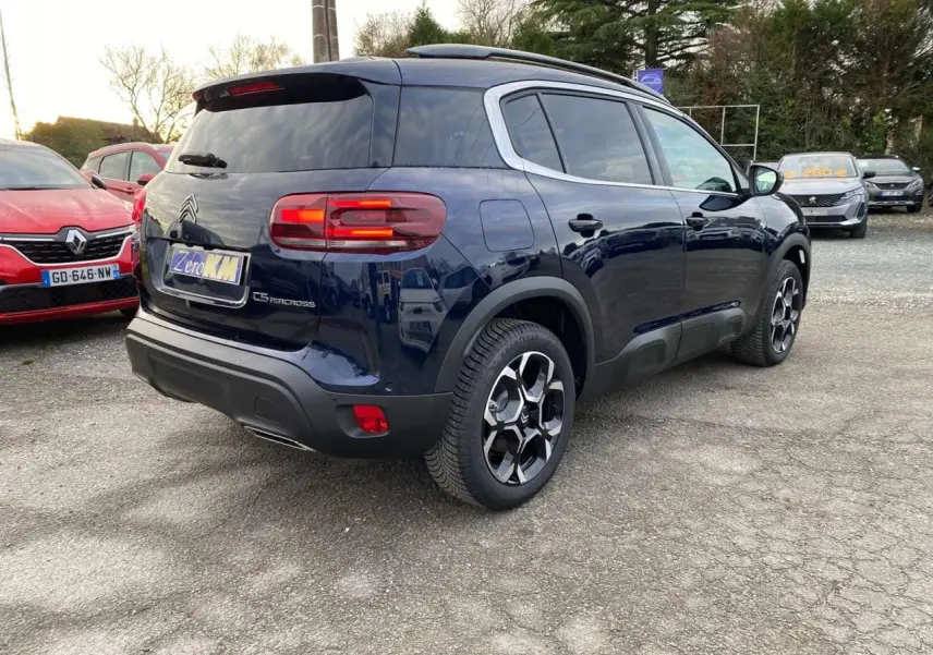 Vue 3/4 arrière droite d'un Citroën C5 Aircross bleu éclipse avec vitres surteintées et jantes alliage distinctives.