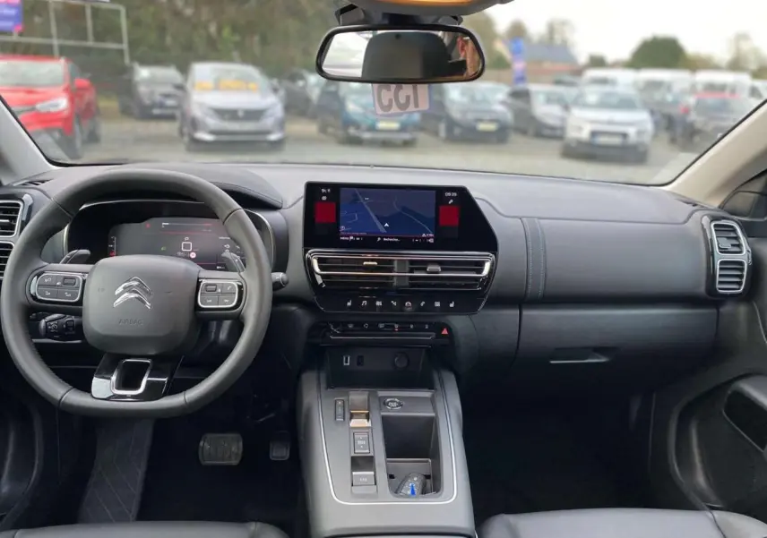 Intérieur du Citroën C5 Aircross 2025 vu de face, tableau de bord noir avec écran tactile de navigation allumé.