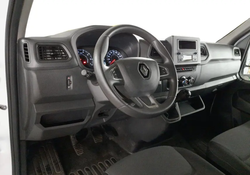 Vue intérieure côté conducteur du Renault Master 2024 blanc, montrant le volant, tableau de bord et levier de vitesses manuel.
