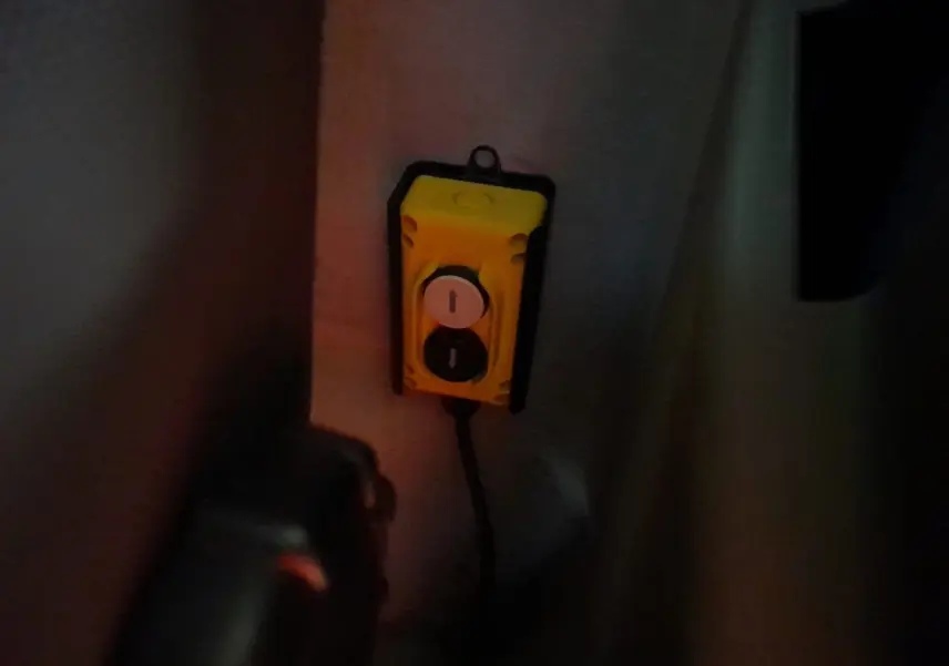 Télécommande jaune avec deux boutons fléchés, fixée à l'intérieur d'une Renault Master blanche 2024, vue rapprochée.