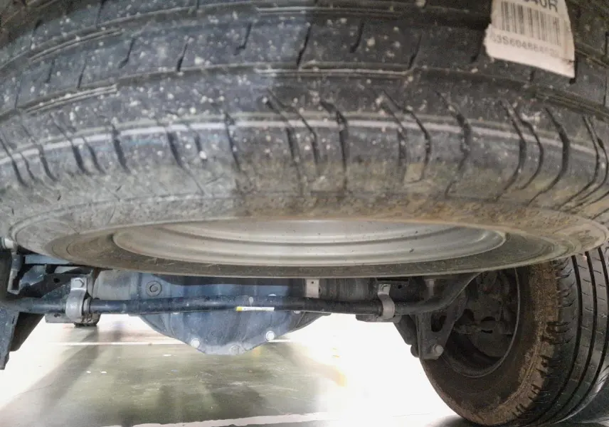 Vue en contre-plongée sous le Renault Master blanc 2024, montrant la roue de secours et le train arrière.