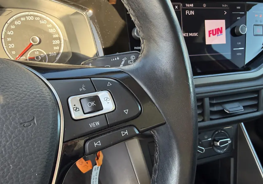 Gros plan sur le volant et le tableau de bord d'une Volkswagen Polo gris métal 2021, avec écran tactile et commandes au volant.