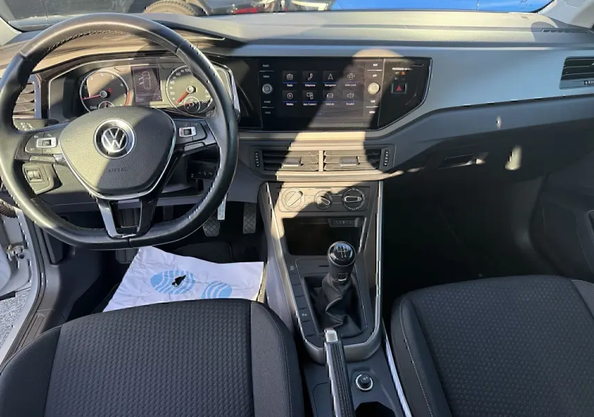Vue intérieure avant de la Volkswagen Polo 1.0 TSI 95 Lounge Business 2021, volant, tableau de bord et boîte manuelle visibles.