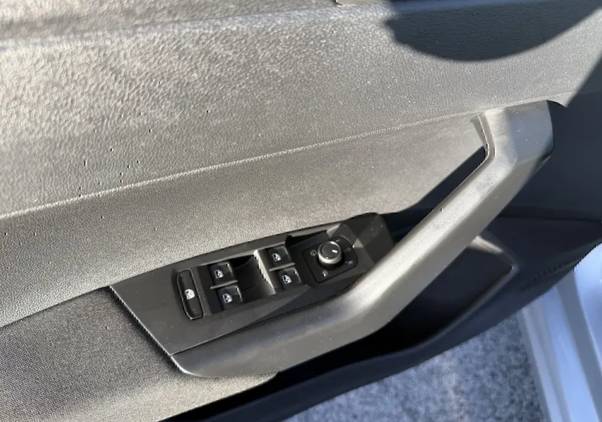 Détail des commandes des vitres et rétroviseurs sur la portière côté gauche d’une Volkswagen Polo gris métal 2021.