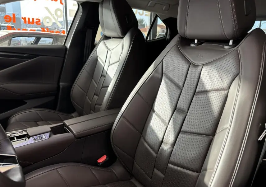 Vue rapprochée des sièges avant en cuir brun Nappa du DS4 E-Tense 2023 avec accoudoir central et surpiqûres visibles.