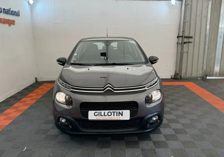 Citroën C3 gris foncé vue de face dans un garage avec phares et antibrouillards allumés.