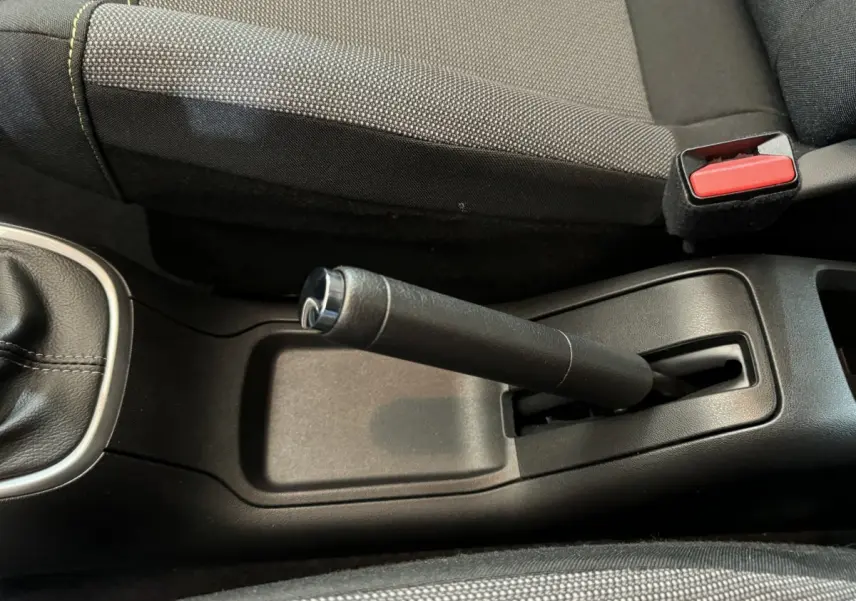 Vue rapprochée de la poignée de frein à main et de la ceinture de sécurité rouge dans l’habitacle gris foncé d’une Citroën C3 2020.