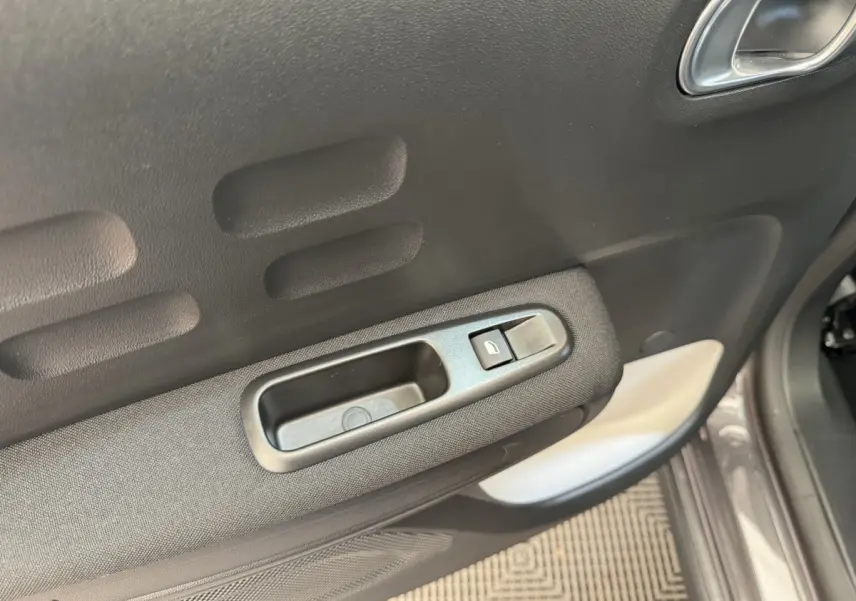 Gros plan sur la poignée intérieure et le bouton de verrouillage de la porte côté conducteur d'une Citroën C3 gris foncé.