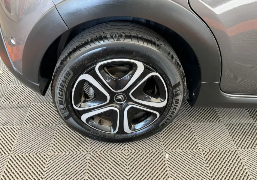 Gros plan sur la roue avant gauche d'une Citroën C3 gris foncé avec jante alliage noire et argentée.