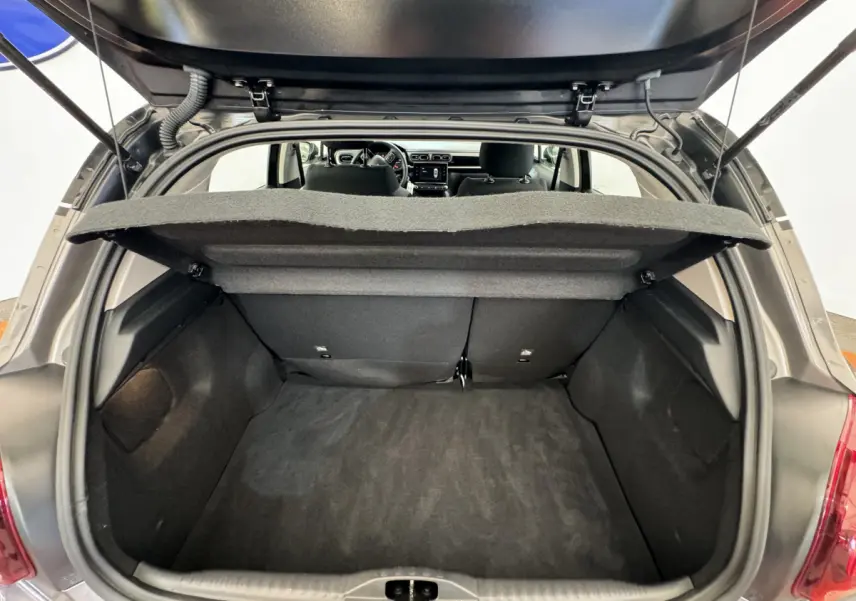 Vue arrière du coffre ouvert d'une Citroën C3 gris foncé, montrant l'espace de chargement et l'intérieur des sièges arrière.