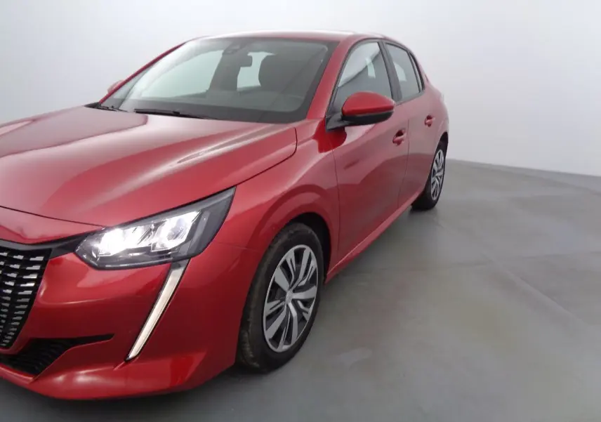 Peugeot 208 rouge Elixir métal vue 3/4 avant droit avec phares allumés sur fond neutre.