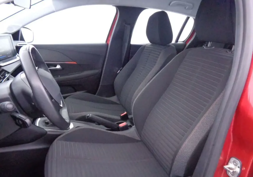 Intérieur avant droit de la Peugeot 208 rouge Elixir Metal, montrant les sièges tissu gris et le volant.