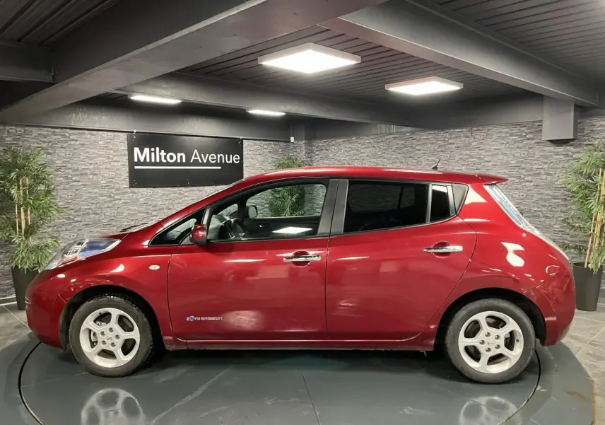 Profil côté gauche d'une Nissan Leaf 30 Visia rouge métallisée, soulignant ses jantes blanches et la mention zéro émission.