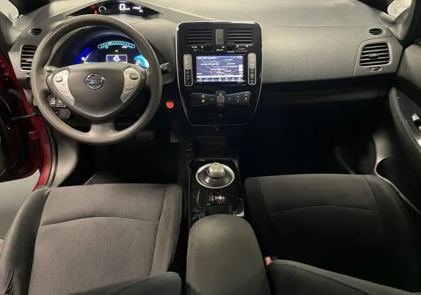 Vue intérieure avant de la Nissan Leaf 30 2017 rouge, mettant en valeur le tableau de bord et la console centrale noire.