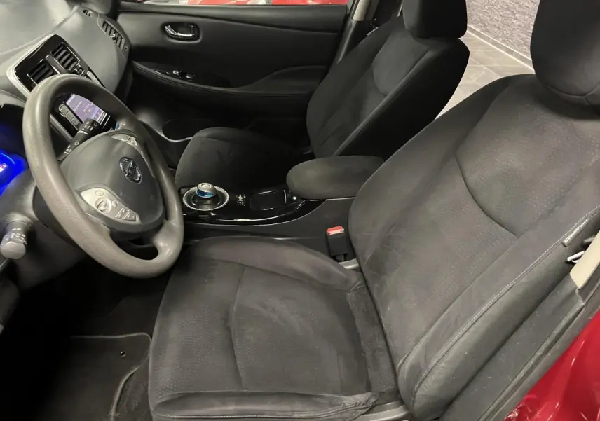 Intérieur avant droit d'une Nissan Leaf 2017 rouge, sièges tissu noirs et volant multifonction avec commandes intégrées.