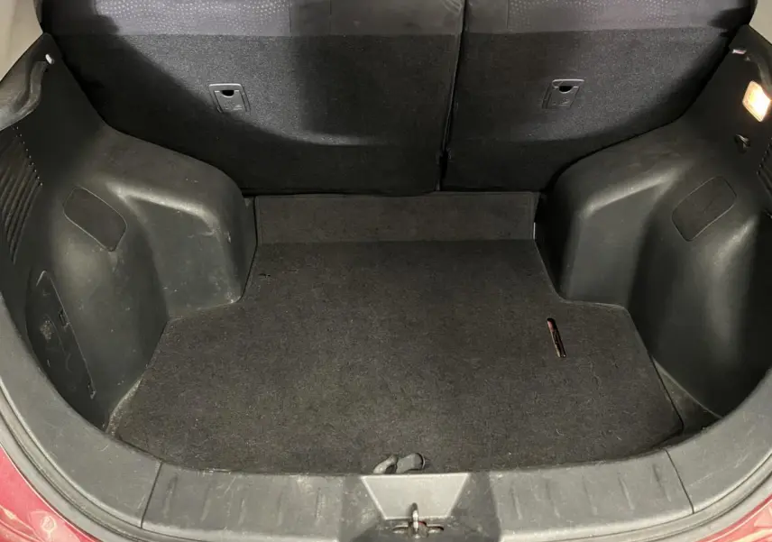 Coffre ouvert vu de face d'une Nissan Leaf rouge 2017, montrant l'espace de chargement vide et la garniture noire.