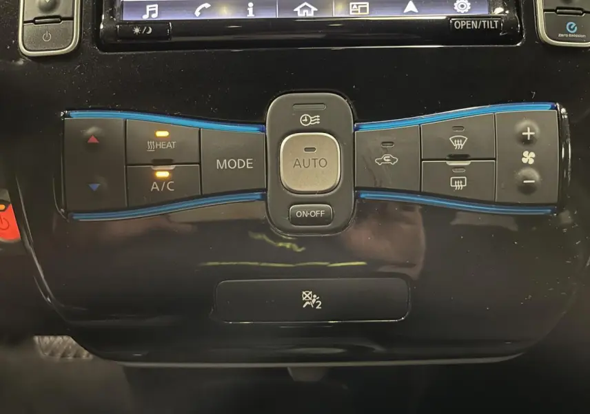 Panneau de commande de climatisation automatique noir de la Nissan Leaf 30 2017 Visia avec boutons éclairés en orange.