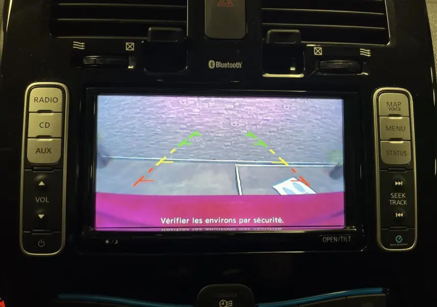 Vue de l'écran de recul du Nissan Leaf rouge 2017, affichant les lignes de guidage colorées pour la marche arrière.