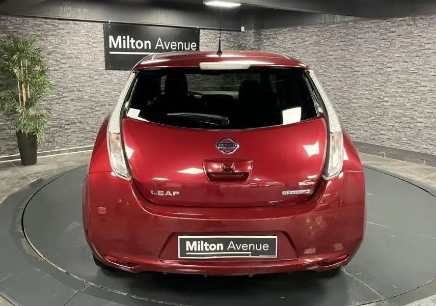 Vue arrière d'une Nissan Leaf rouge métallisée 2017 avec logo et badges électriques visibles en intérieur showroom.