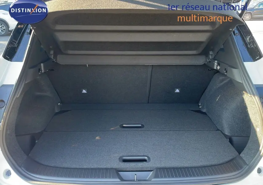 Coffre ouvert d'un Nissan Qashqai blanc nacré avec toit noir, vue arrière montrant un espace de chargement plat et spacieux.
