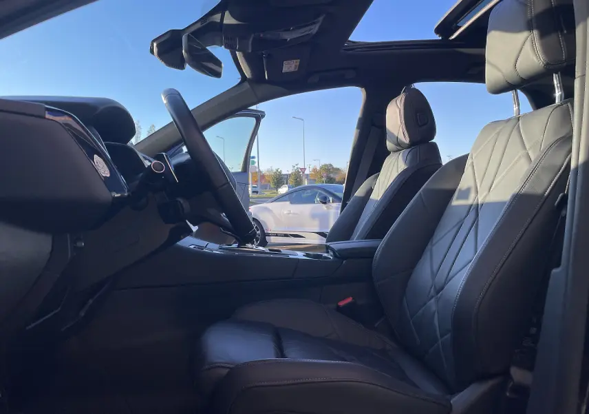 Vue intérieure côté conducteur du DS7 2024 noir Perla Nera, mettant en valeur les sièges cuir noir et le toit ouvrant panoramique.