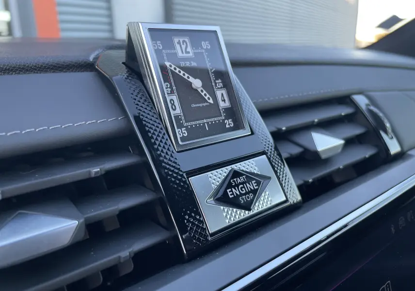 Gros plan sur l'horloge BRM et le bouton Start Engine Stop du tableau de bord noir du DS7 2024.