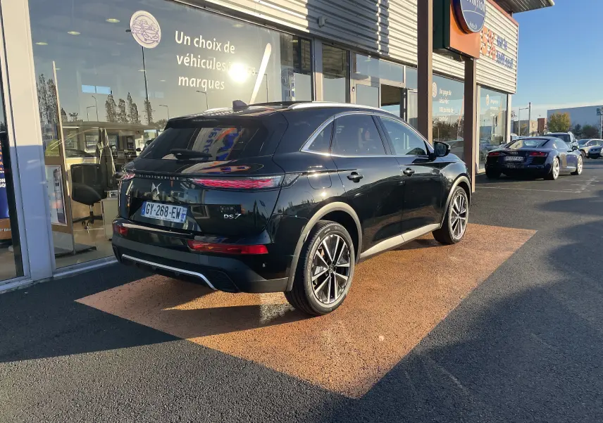 Vue 3/4 arrière droite d'un DS7 noir Perla Nera 2024, avec feux arrière DS Pixel Led Vision 3.0, stationné devant un showroom.