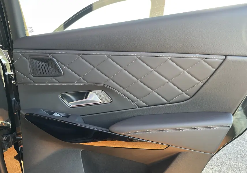 Gros plan sur la garniture en cuir noir matelassé de la porte arrière gauche du DS7 2024 Noir Perla Nera.