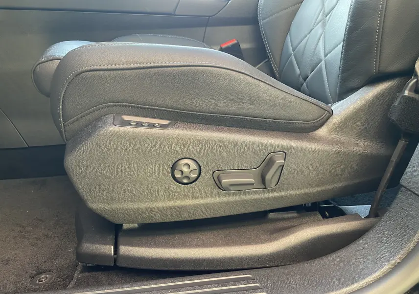 Gros plan sur les commandes de réglage électrique du siège avant gauche en cuir noir du DS7 2024 Noir Perla Nera.