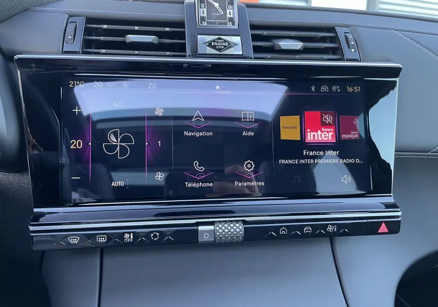 Écran tactile central du DS7 2024 noir Perla Nera, affichant la climatisation et la radio France Inter, avec horloge analogique intégrée.