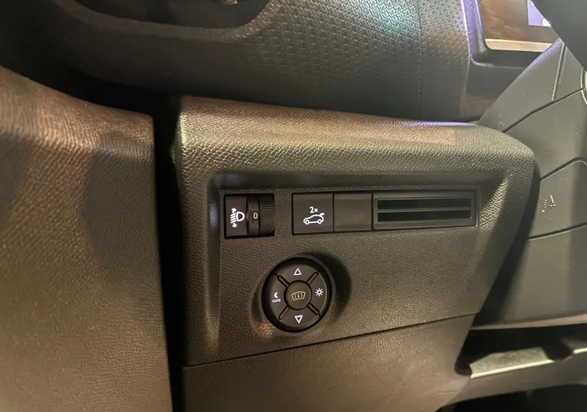 Détail du tableau de bord côté gauche du Citroën C4 X gris 2024, avec commandes d'éclairage et réglage des rétroviseurs.