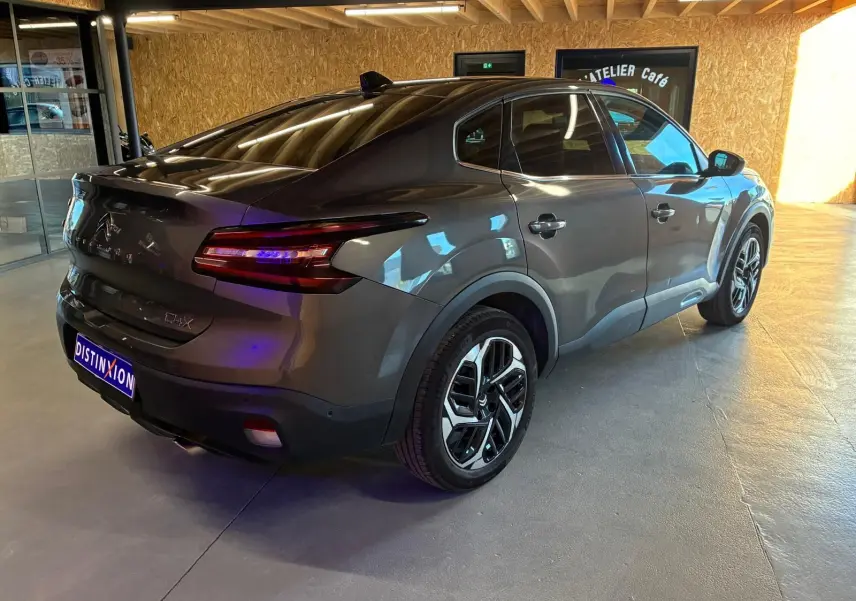 Vue 3/4 arrière droite d'une Citroën C4 X gris métallisé 2024 avec feux arrière LED et jantes alliage distinctives.