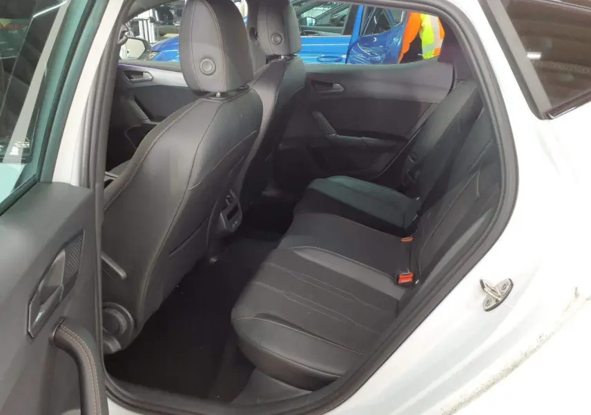 Vue intérieure côté arrière droit de la CUPRA Leon blanche Nevada, montrant les sièges arrière en cuir noir avec surpiqûres contrastées.