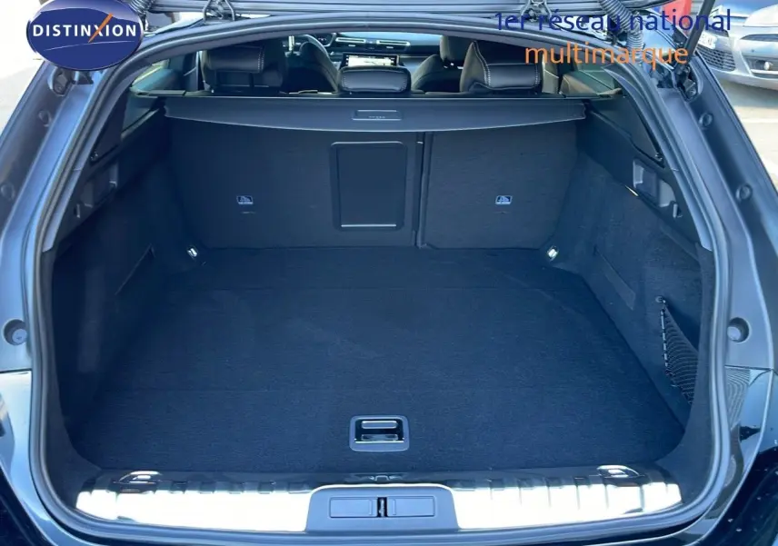 Coffre ouvert vu de l'arrière d'une Peugeot 508 SW noire, montrant un espace de chargement spacieux et propre.