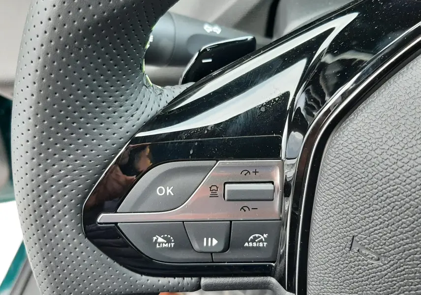 Gros plan sur les commandes gauche du volant perforé noir du Peugeot 308 1.2 Hybrid 145ch GT 2025.