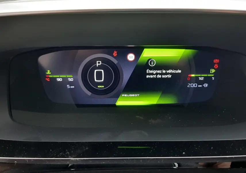 Tableau de bord numérique du Peugeot 308 hybride 2025 affichant la vitesse à zéro et un message d'arrêt du véhicule.