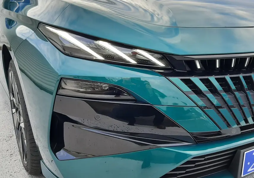 Vue 3/4 avant gauche d'une Peugeot 308 1.2 Hybrid 145ch GT bleu Lagoa avec phares LED et calandre noire brillante.