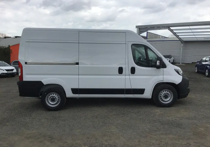 Peugeot Boxer Fourgon blanc vu de profil côté gauche, avec portes coulissantes et protections noires sur bas de caisse.