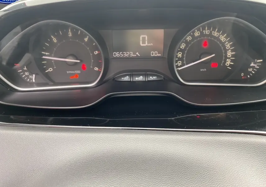 Vue rapprochée du tableau de bord de la Peugeot 208 Affaire noir, affichant le compteur et l'odomètre à 65323 km.