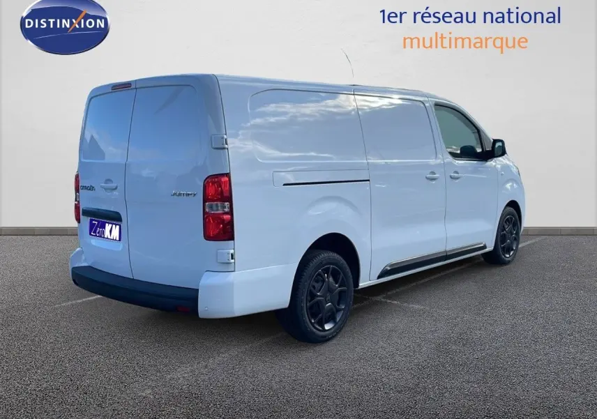 Vue 3/4 arrière droite d'un Citroën Jumpy Fourgon XL blanc Kaolin avec jantes noires et portes latérales fermées.