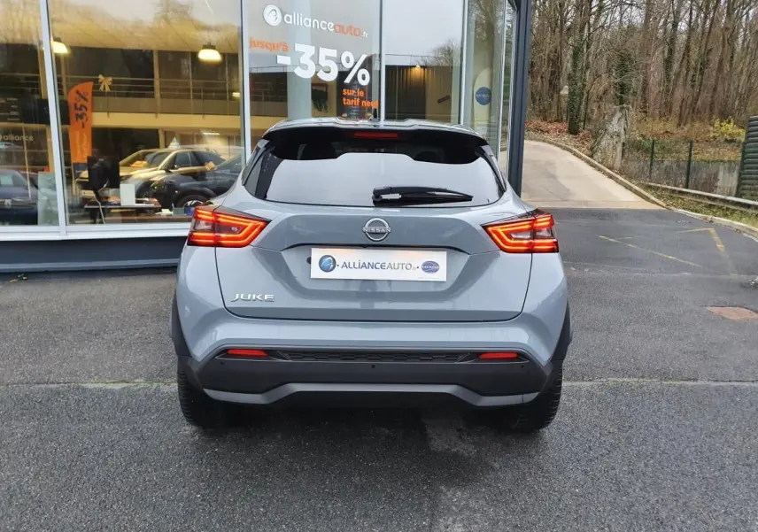 Vue arrière d'un Nissan Juke gris céramique 2025 avec feux LED allumés et vitrage arrière teinté.