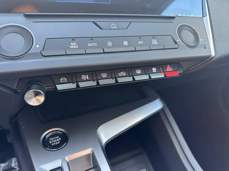 Vue rapprochée de la console centrale de la Peugeot 308 2025 bleu, montrant les commandes climatisation et bouton démarrage.